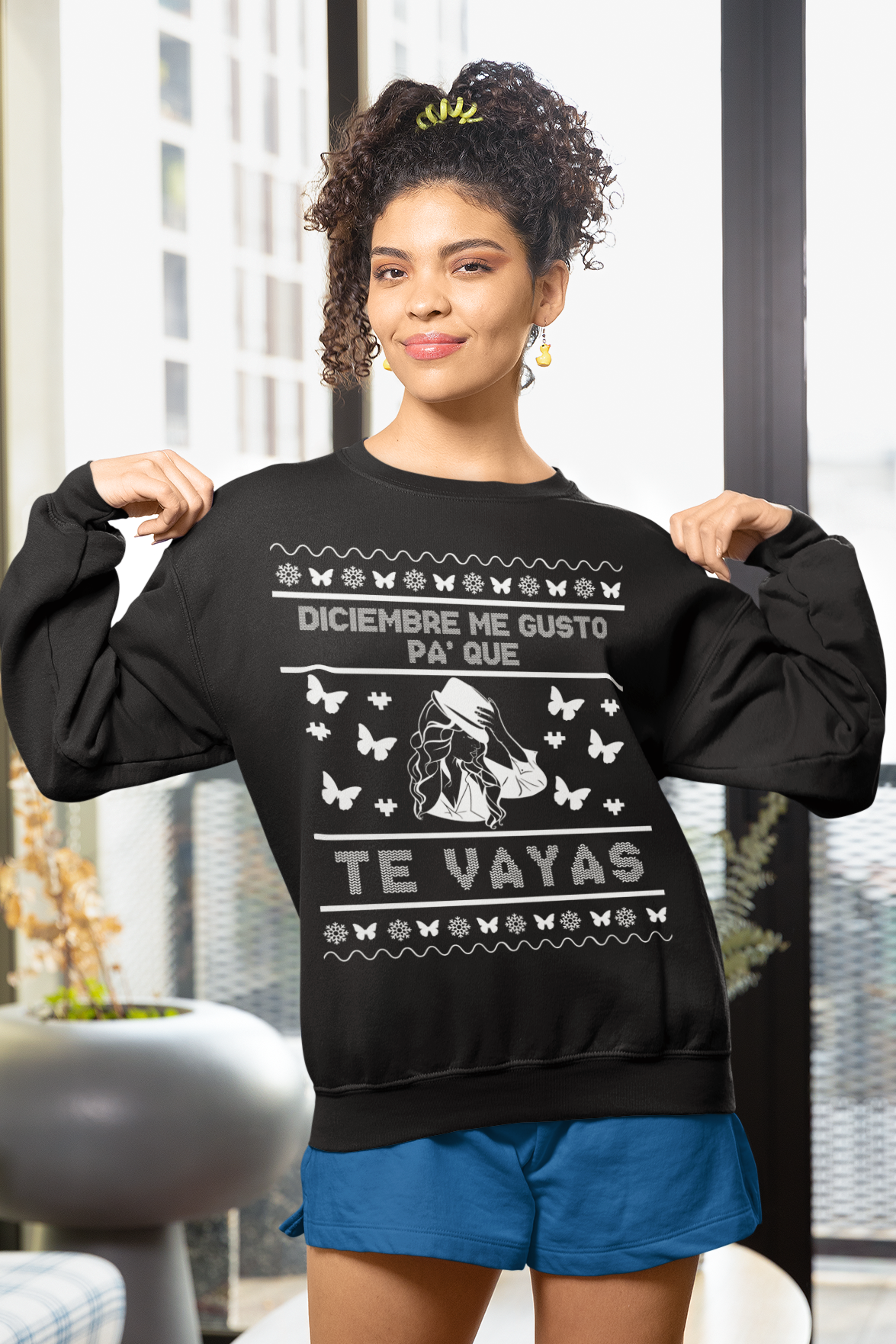 Woman wearing a black sweatshirt with white text and graphics, standing indoors.