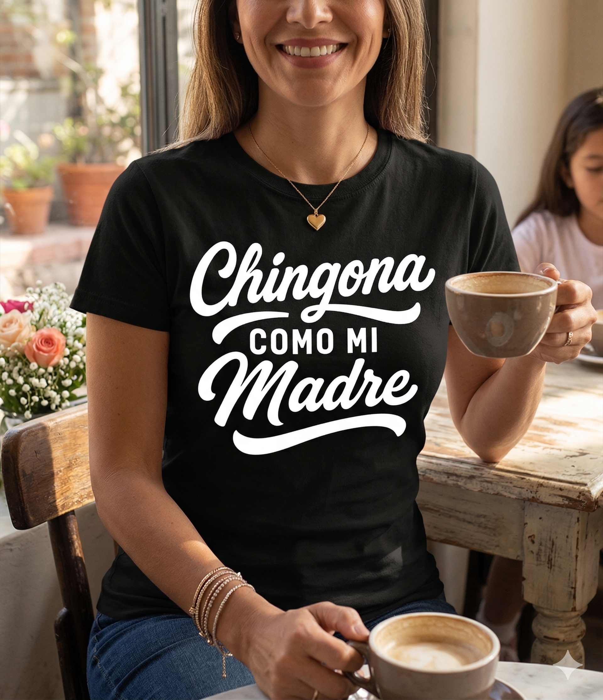 Woman wearing a black t-shirt with 'Chingona Como Mi Madre' text, holding a coffee cup indoors.