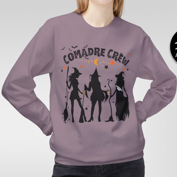 Person wearing a purple sweatshirt with 'Comadre Crew' design, standing against a plain background.