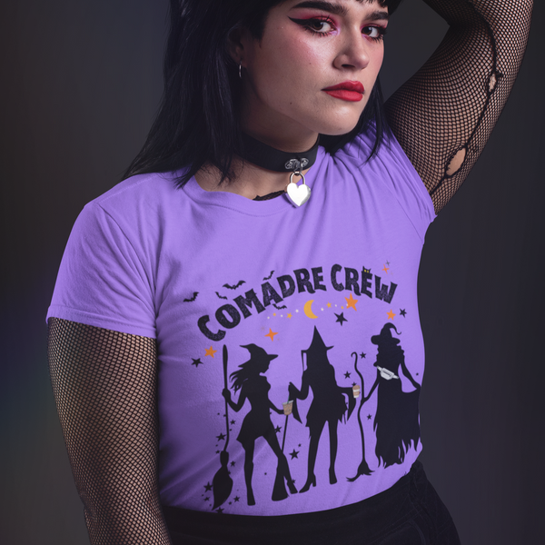 Person wearing a purple t-shirt with 'Comadre Crew' design against a dark background